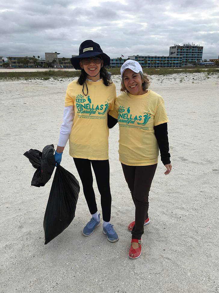 Two ladies smiling at the camera after cleaning the beach.