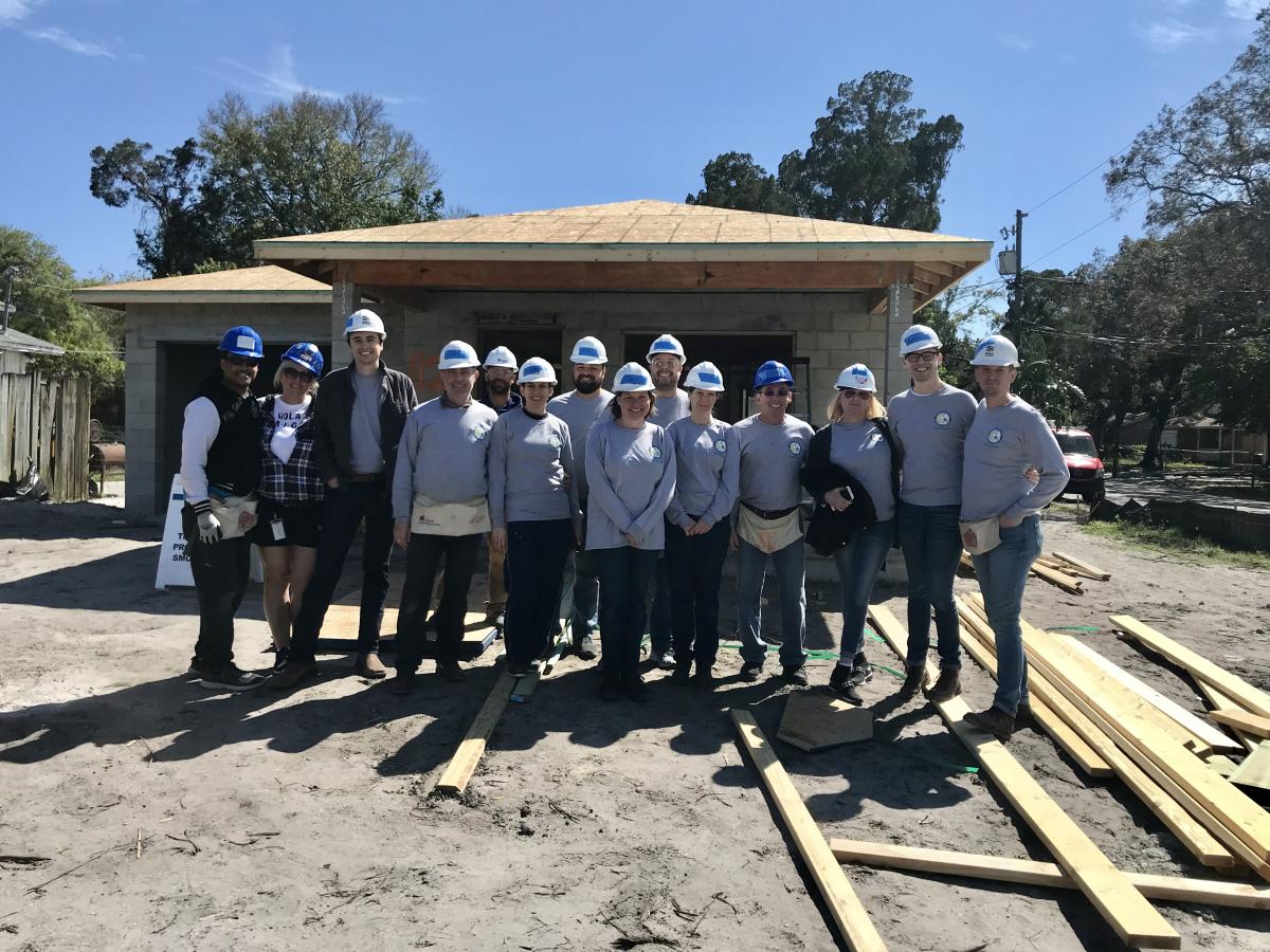 PAO employees smiling at the camera in front of the home they helped build.